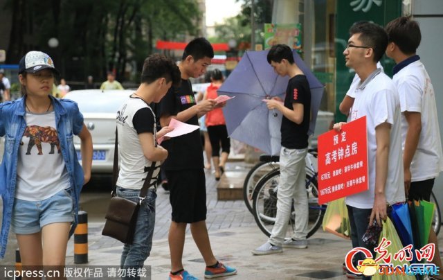 2014年6月6日下午，北京，高考考点北大附中路口的两边人行道上，几位“黄牛”冒雨向过往的家长人群宣传高考钟点房。