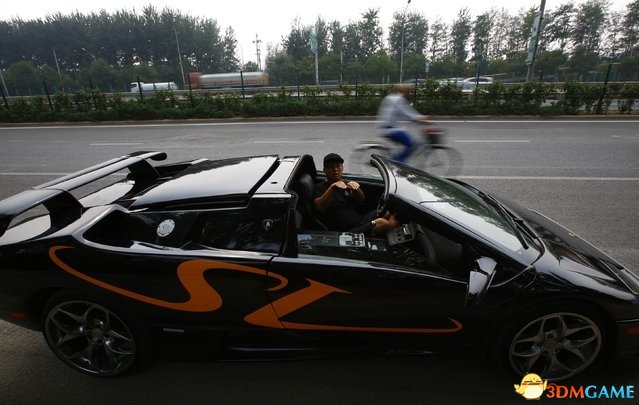 2014年8月21日，北京，试驾期间，王宇正坐在其自制的兰博基尼Diablo超跑中打手势，一名骑自行车的人正从街道的一旁经过。